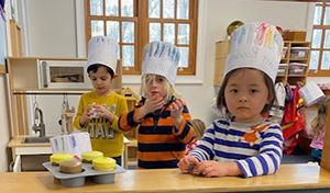 Children in play bakery wearing chefs hats